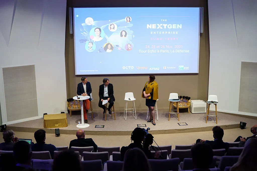 On stage at the NextGen Enterprise Summit 2021: three speakers in front of an audience, the Summit's title on the screen behind them